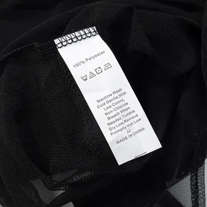 Detailopname van wit waslabel met 100% polyester tekst op zwarte mesh kledingstuk stof