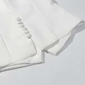 Close-up of white short-sleeved tweed-style top showing elegant fabric texture and buttons.