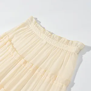 Macro detail of a cream-colored tiered chiffon maxi skirt showing the ruffled waistband