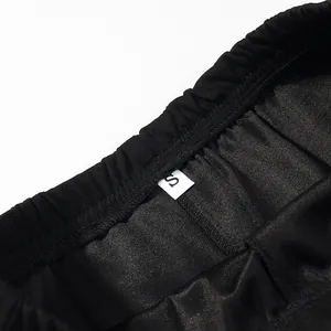 Primo piano del dettaglio dell'elastico in vita e dell'etichetta S sui pantaloni neri