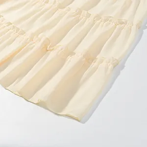 Close-up detail showing the tiered ruffle layers and chiffon texture of the cream skirt