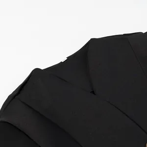 Primo piano del top nero con maniche a sbuffo che mostra la trama del tessuto e le cuciture.