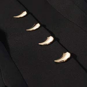 Dettaglio bottoni dorati a goccia su tessuto nero per un elegante set con maniche a sbuffo.