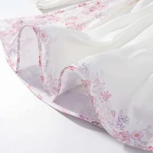 Primer plano del dobladillo de un vestido blanco con delicado estampado floral rosa