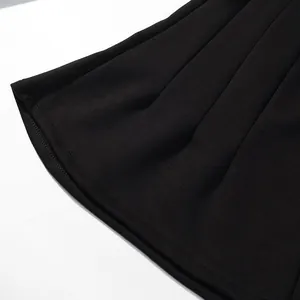 Macro view of the hem and pleated fabric of black wide-leg trousers