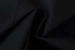 Close-up detail of high-quality black blazer fabric showing fine weave and elegant drapes.