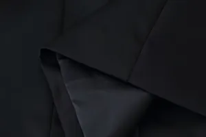 Detailed macro shot showing the premium texture and weave of black blazer fabric