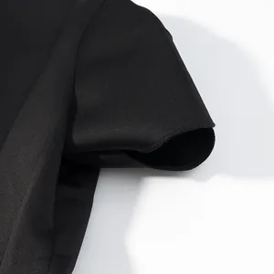 Dettaglio ravvicinato del tessuto nero liscio e delle cuciture di un top con maniche a sbuffo.