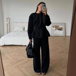 Full view of elegant black long-sleeve peplum top and wide-leg trousers set on a model.