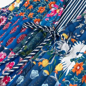 Detail of floral quilted vest with striped tie-up closure and colorful prints.