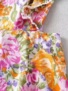 Nahaufnahme eines sommerlichen Kleides mit Blumenmuster, Rüschen und weißem Bommel-Saum-Detail