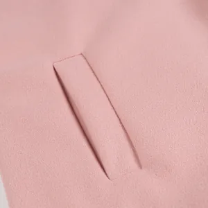 Detailansicht der Tasche und Stoffstruktur eines rosa Wollmantels