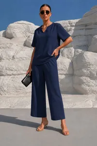 Vista dettagliata del completo con top blu scuro con scollo a V e pantaloni a gamba larga.