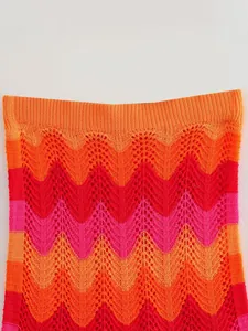 Gros plan sur le détail d'un tissu en maille crochetée chevron rose et orange vif et texturé