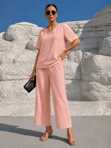 Elegante set vacanza rosa due pezzi con top scollo a V e pantaloni larghi mostrati su modella