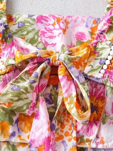Detailaufnahme eines Kleides mit Blumendruck, Schleife und weißem Pompon-Besatz-Stil