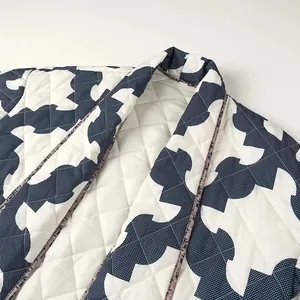 Close-up of quilted kimono jacket featuring blue and white geometric print and soft padding.