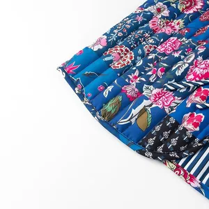 Macro detail of a vibrant floral print quilted sleeveless vest showing stitching and tie-up hem.