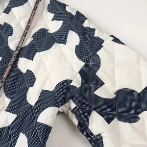 Close-up of quilted diamond stitching and blue geometric print on a white padded jacket.