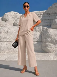 Elegante completo beige con top a V e pantaloni larghi per vacanze su modella all'aperto
