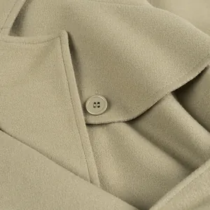 Close-up macro detail of a beige wool coat highlighting the lapel and button texture.
