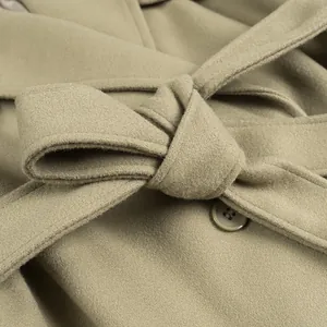 Close-up of a belted waist on a sage green woolen coat showing soft fabric texture