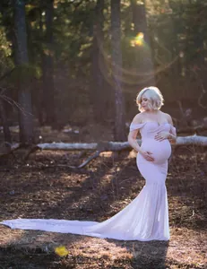 Elegant light pink maternity photography gown with long chiffon train in forest setting