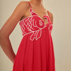 Detail view of red sundress featuring intricate white goldfish embroidery on chest.