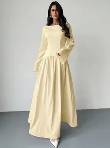 Elegante lange jurk met lange mouwen en boothals in lichtgeel met een A-lijn rok