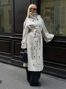 Side view of woman in elegant long double-breasted trench coat with belt in street setting