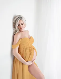 Elegant off-the-shoulder yellow maternity gown with front split for photography sessions