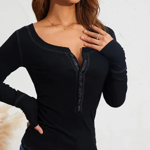 Primo piano di maglia a coste nera a maniche lunghe con dettaglio bottoni eleganti.