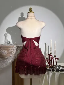 Vue détaillée d'une robe tube à paillettes bordeaux avec nœud au dos et détails de tissu.