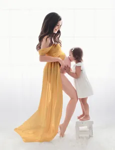 Atmospheric shot of yellow off-shoulder maternity gown on model in a white studio