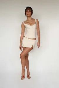 Elegant off-white two-piece corset top and matching mini skirt set worn by a model