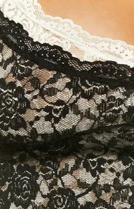 Dettaglio ravvicinato del pizzo floreale nero e del bordo bianco di un vestito aderente chic
