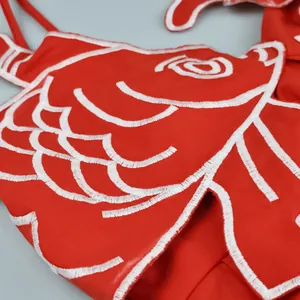 Close-up detail of intricate white goldfish embroidery on a vibrant red sweet-style slip dress