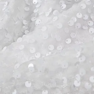 Macro detail showing high-quality white sequined fabric texture for elegant women's jacket