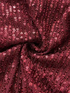 Détail en gros plan de paillettes bordeaux scintillantes sur tissu résille de soirée
