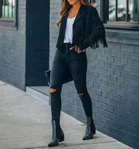 Detail view of a black fringe jacket paired with black ripped skinny jeans and boots