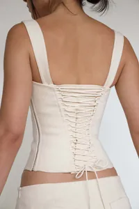 Back view detail of a cream cotton corset top featuring an intricate lace-up tie design