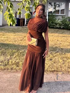 Modell in einem braunen ärmellosen Netz-Maxikleid mit Raffungen im Freien.