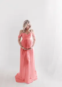 Detailed view of coral pink off-shoulder floor-length maternity photoshoot gown.