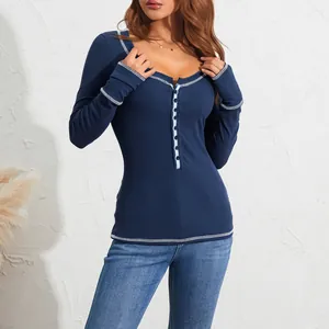 Dettaglio di un top in maglia blu slim fit con cuciture bianche a contrasto e bottoni frontali