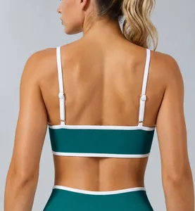 Detailed back view of a ribbed dark green sports bra featuring white trim and adjustable straps
