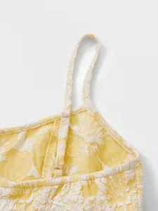 Detail showing the adjustable shoulder strap and 3D floral embossed fabric on a yellow dress
