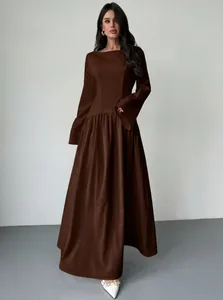 Elegant vooraanzicht van een model in een chocoladebruine maxi-jurk met lange mouwen.