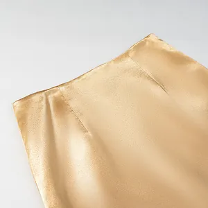 Close-up detail of champagne gold satin skirt waist showing fine fabric and stitching
