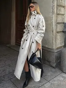 Street style shot of a long cream double-breasted trench coat with a high collar