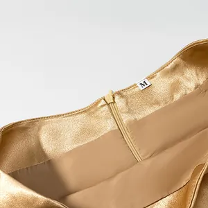 Detailed macro view of metallic gold skirt waistline featuring size M label and zipper